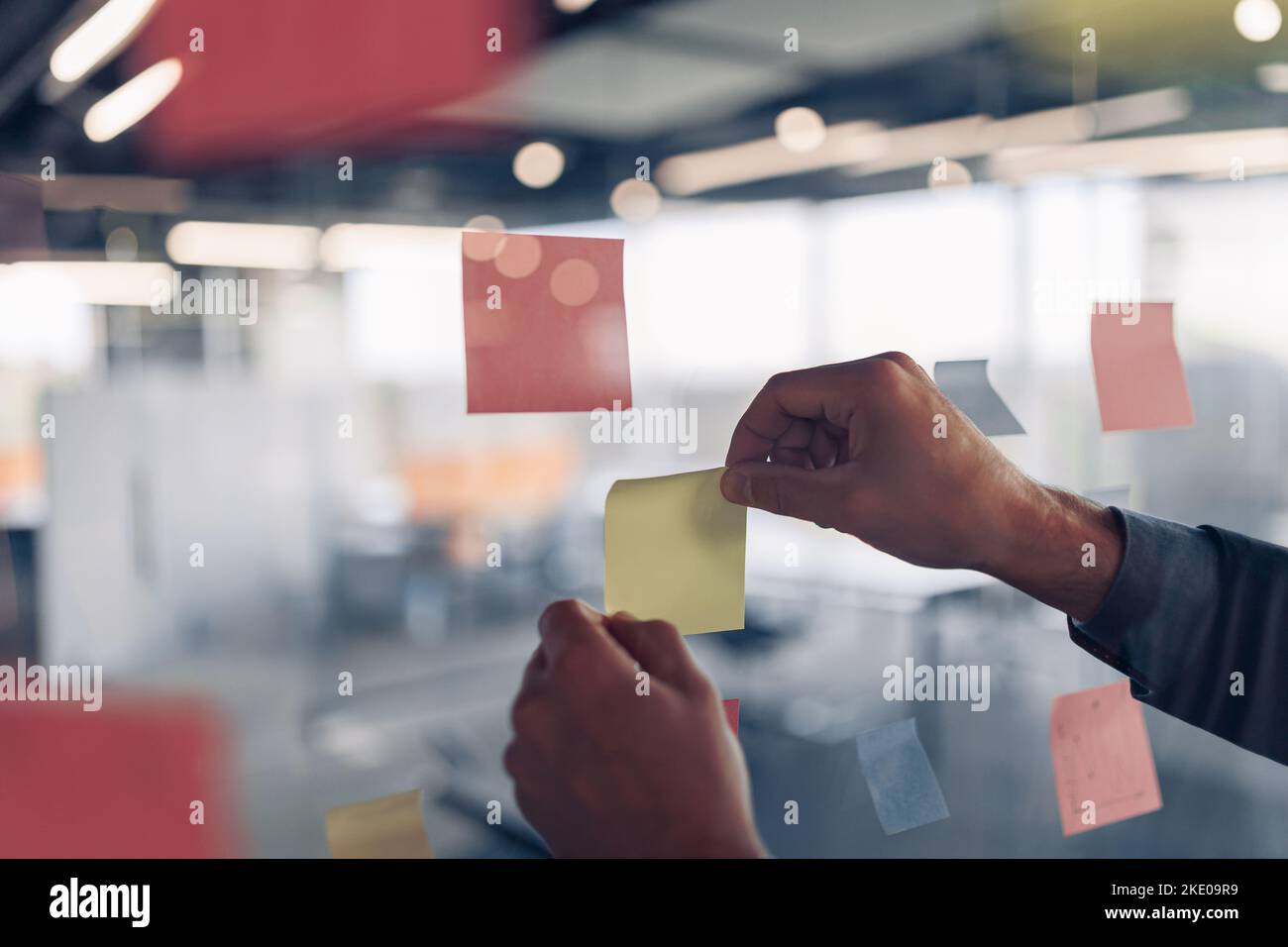 La mano di businesswoman sta attaccando i note appiccicose sul bordo di motivazione in ufficio Foto Stock