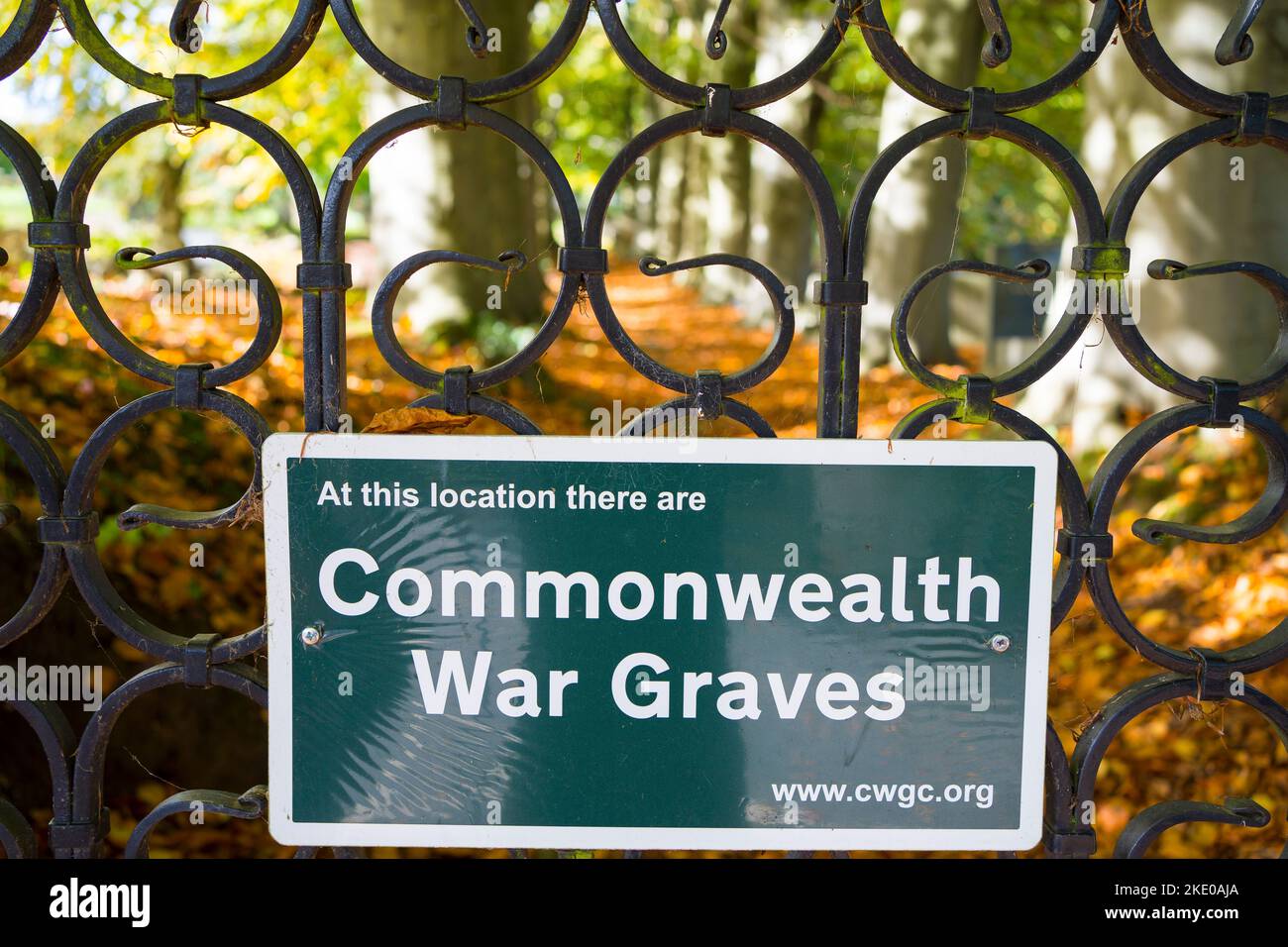 Cimitero di guerra Commonwealth posizione tombe. Guardando attraverso cancelli d'acciaio ornati in un giorno di autunno soleggiato. Foto Stock