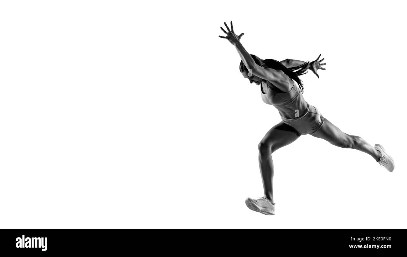 Velocità e potenza. Ritratto in bianco e nero di atleta professionista, runner, jogger in azione isolato su sfondo bianco. Monocromatico. Foto Stock