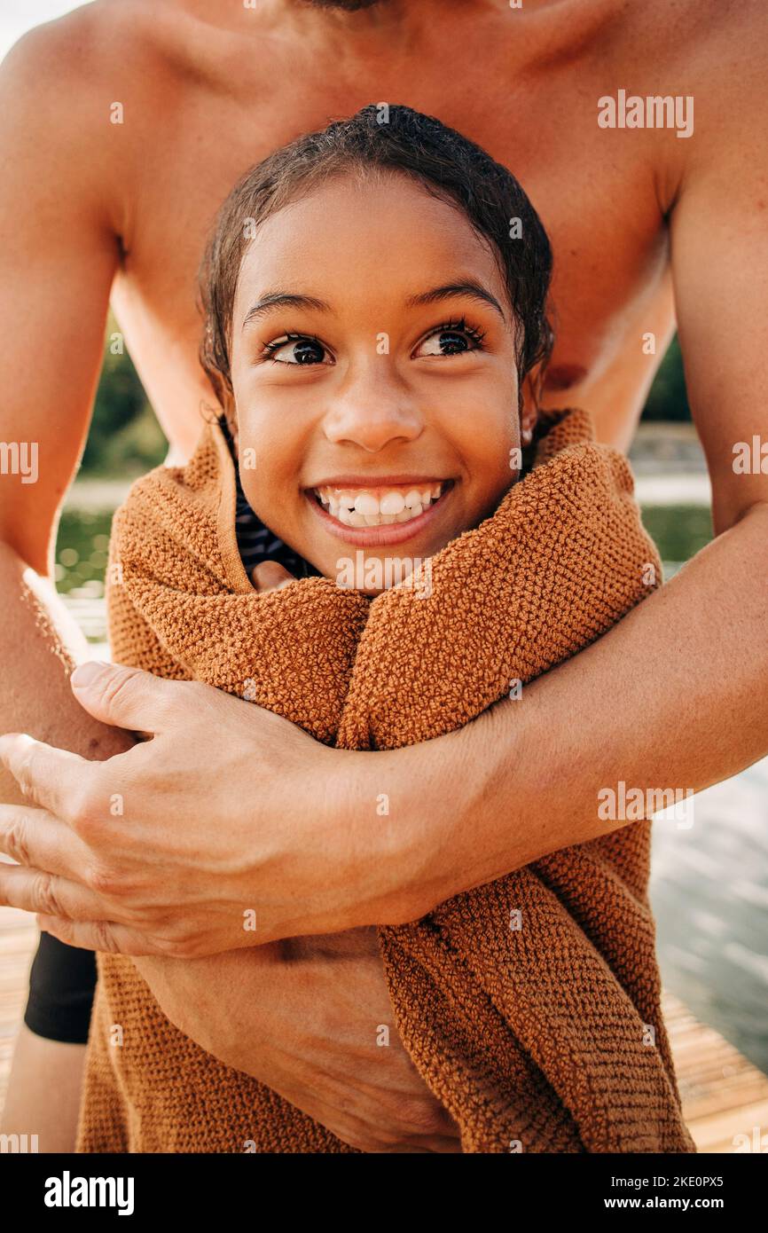 Padre abbracciando la figlia avvolta in asciugamano Foto Stock