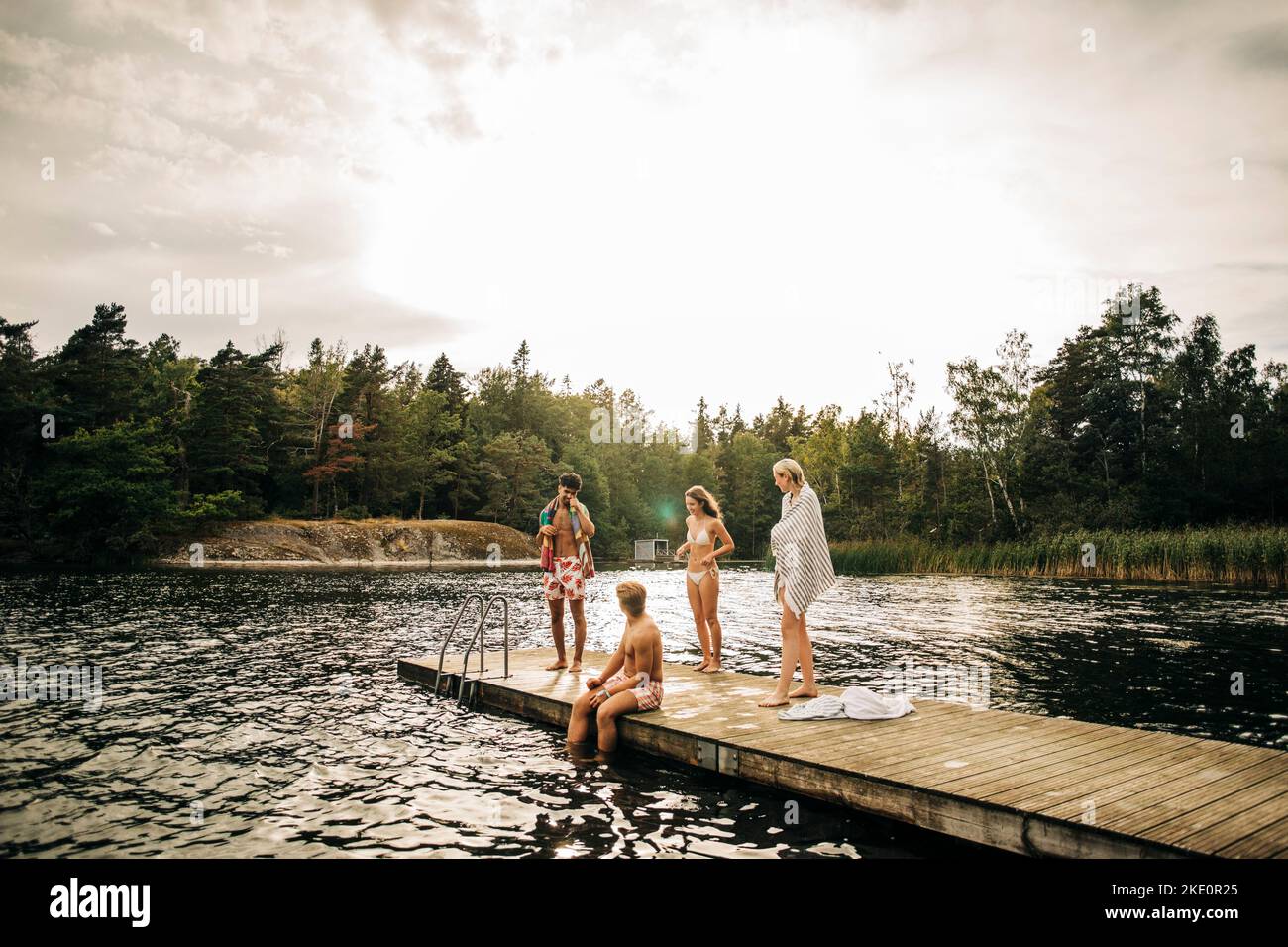 Amici sul molo mentre si godono le vacanze al lago Foto Stock