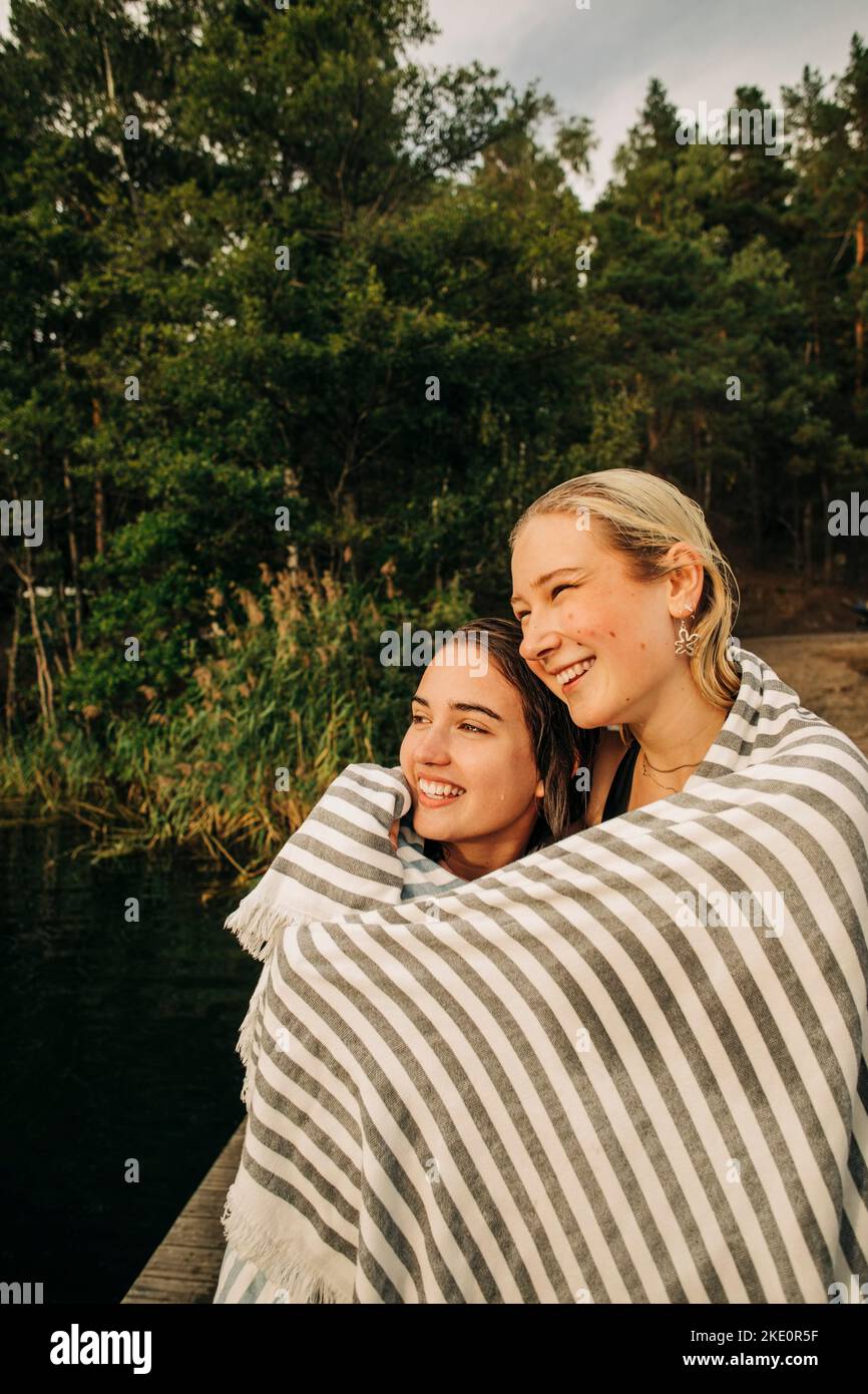 Sorridenti giovani amici fasciati in asciugamano durante le vacanze Foto Stock