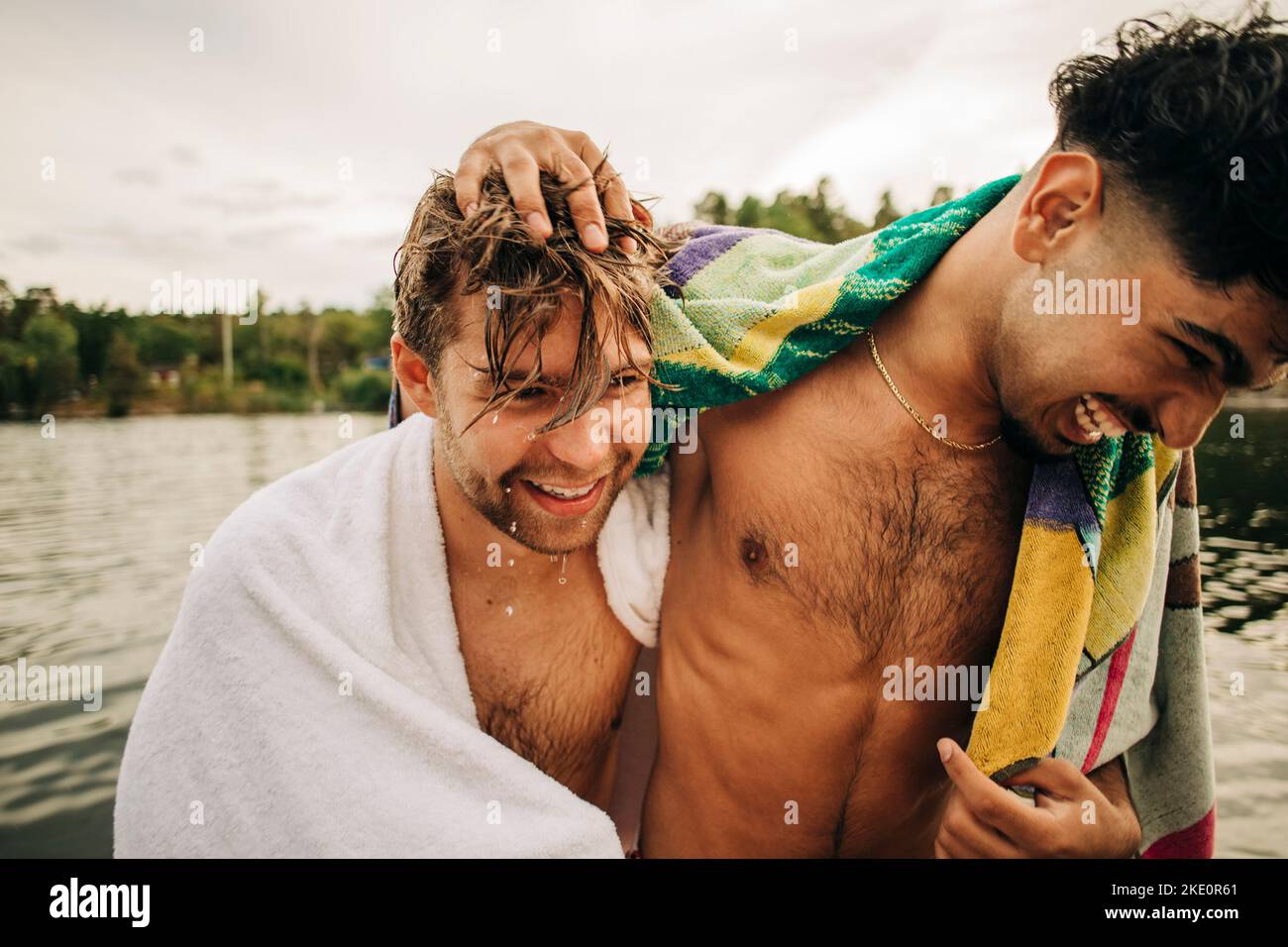 Amici maschi felici che indossano asciugamano godendo durante le vacanze Foto Stock