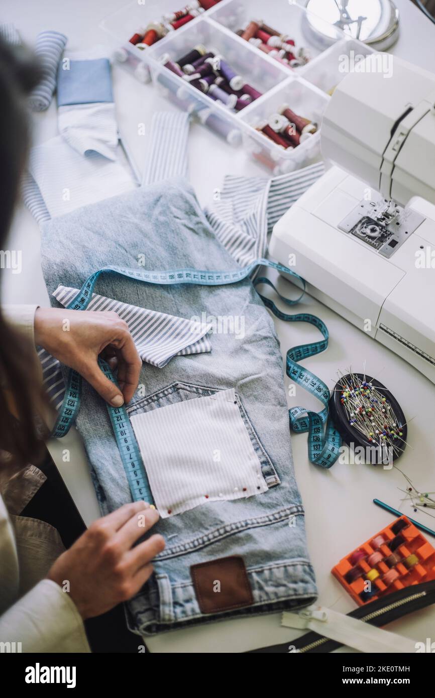 Vista ad angolo alto del design professionale misurazione tasca posteriore di jeans in officina Foto Stock