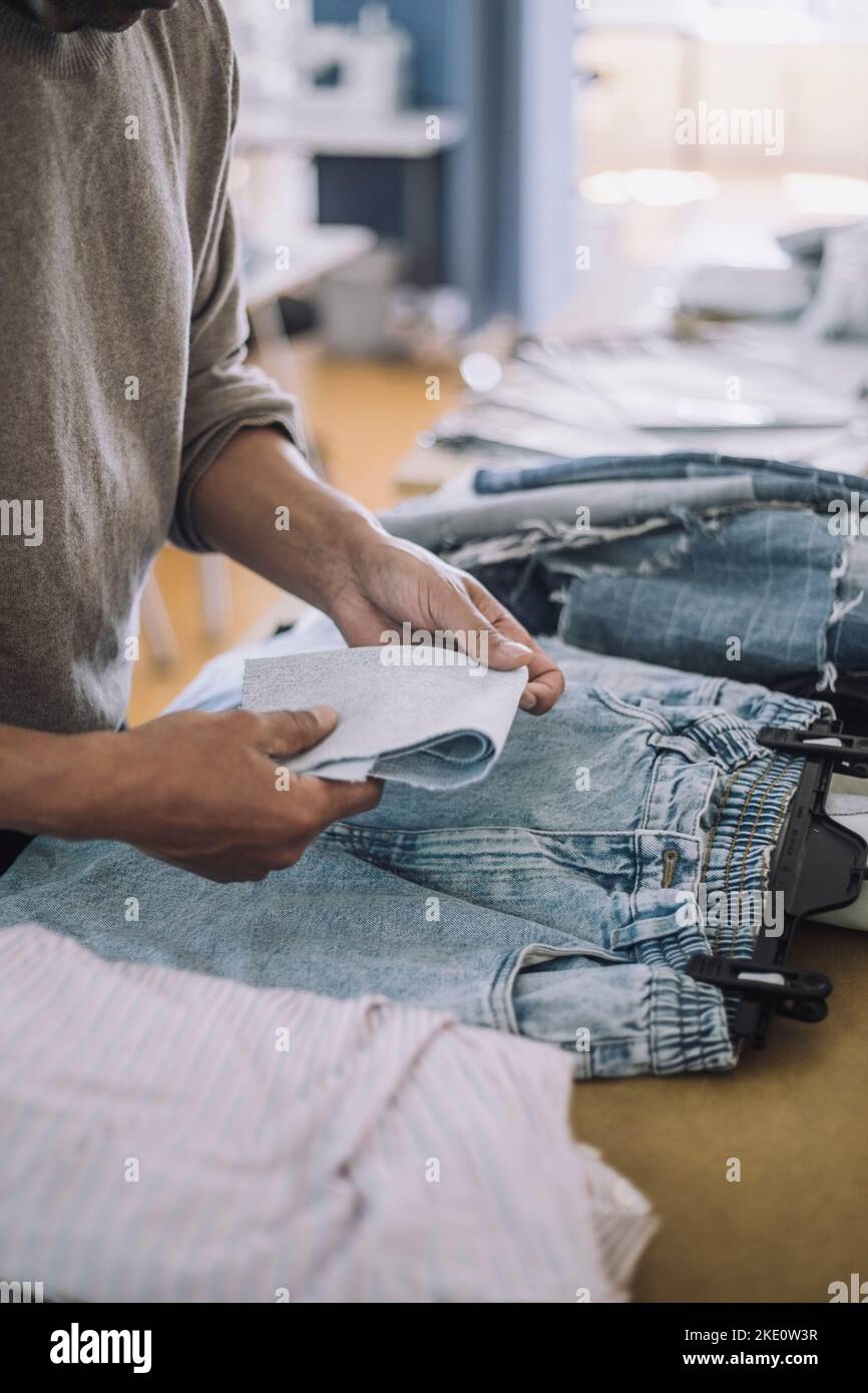 Tessuto pieghevole moda maschile con jeans sul banco di lavoro in officina Foto Stock