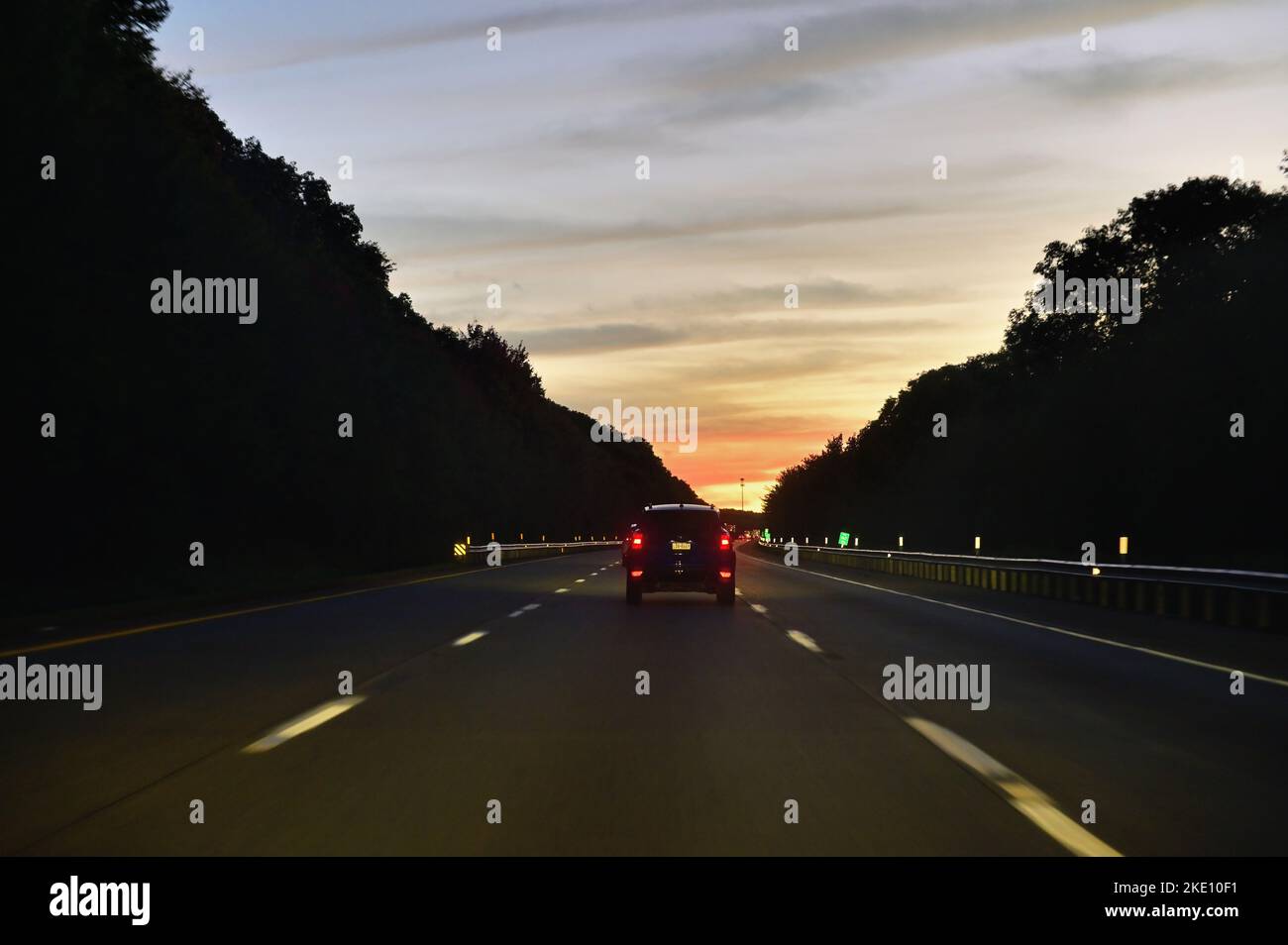 Pennsylvania, Stati Uniti. Un solo veicolo si dirige verso il tramonto su un'autostrada interstatale attraverso un tratto rurale della Pennsylvania. Foto Stock