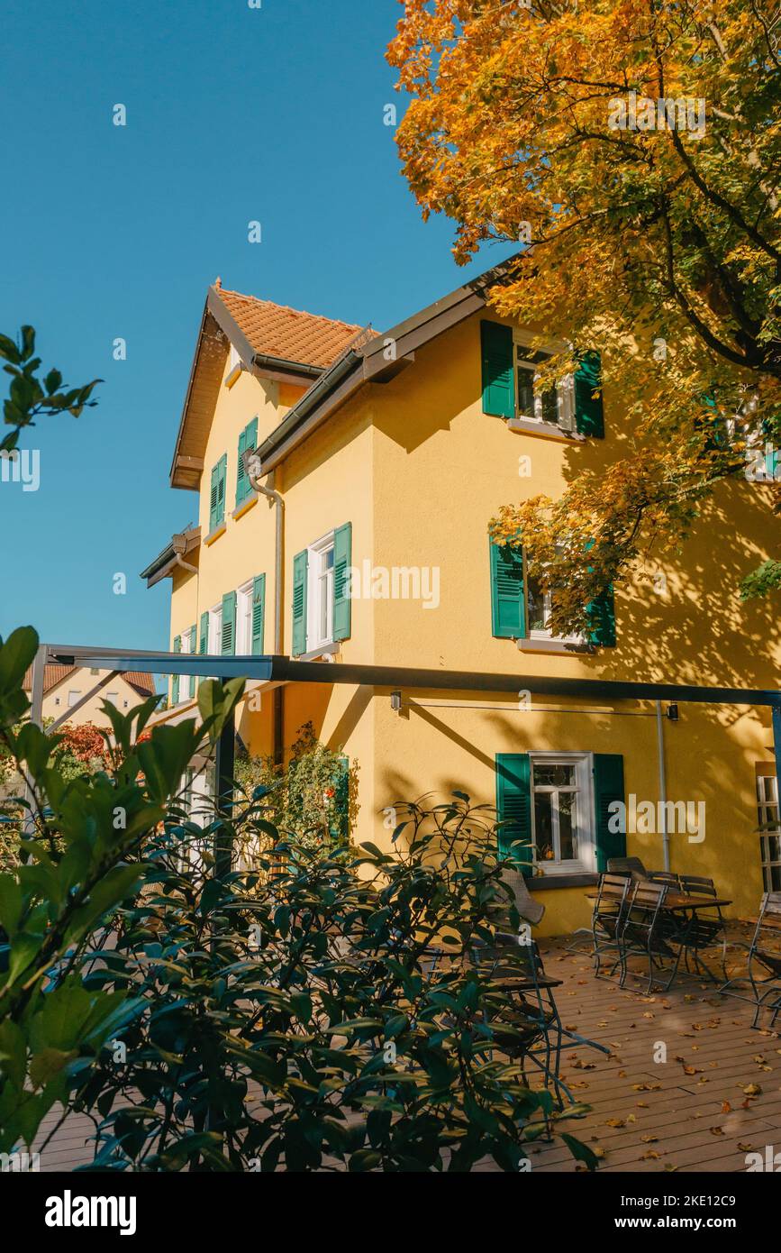 Immagine di tavoli da caffè vuoti disposti nel cortile di una casa. Autunno in Germania, Europa. Tavolo all'aperto in Street cafè. Caffè all'aperto autunnale in legno Foto Stock