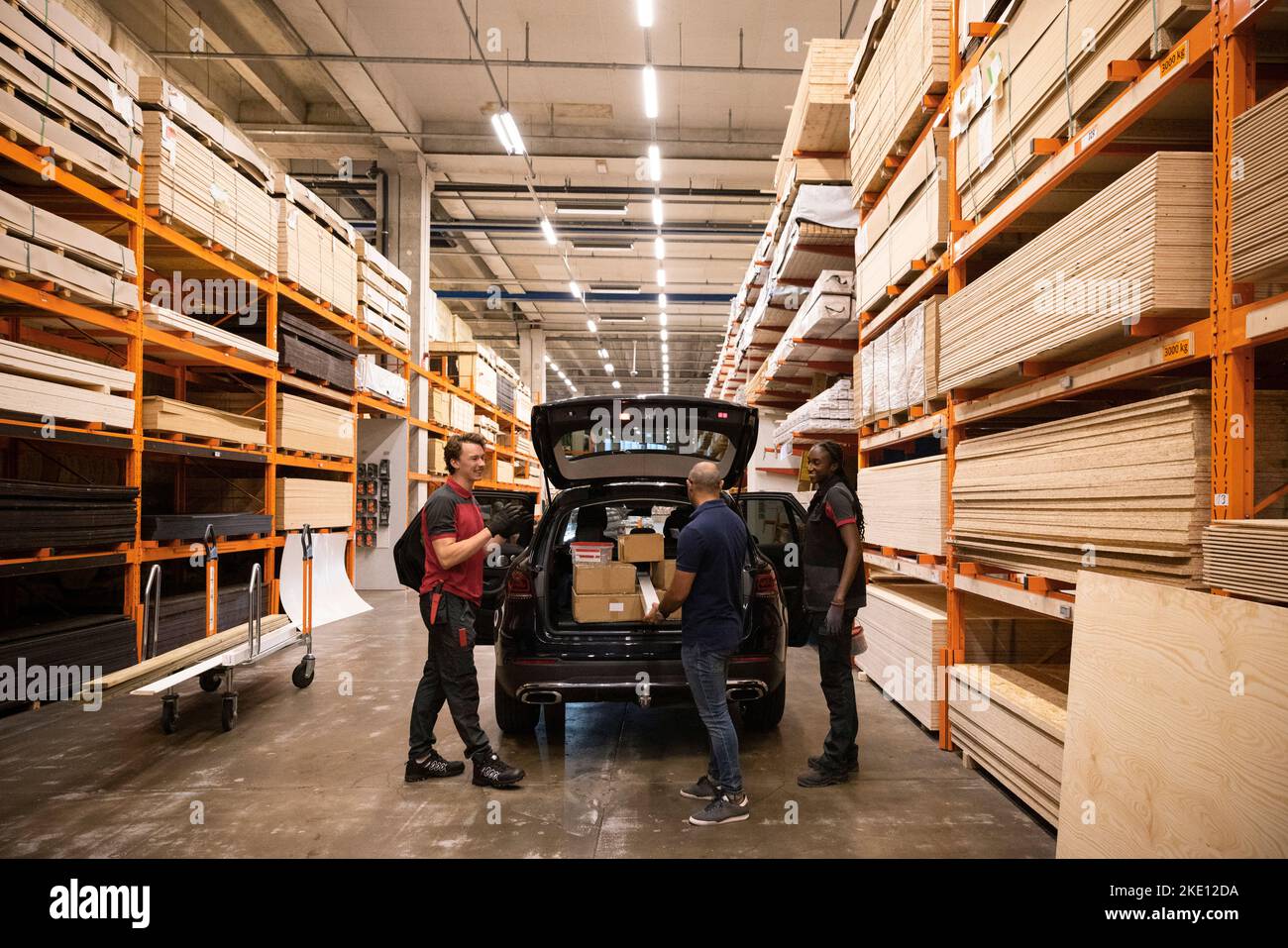 Il personale addetto alle vendite comunica con il cliente che si trova vicino all'auto presso il negozio di hardware Foto Stock