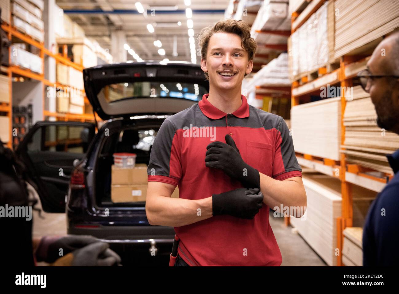 Un venditore sorridente che guarda lontano mentre parla con il cliente presso un negozio di hardware Foto Stock