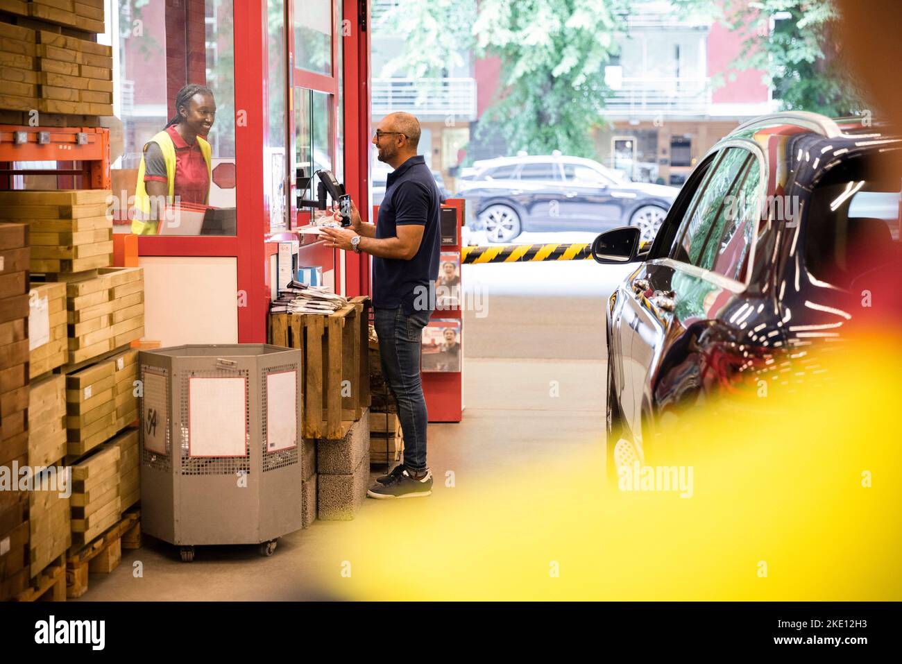 Vista laterale del cliente che parla con il personale di vendita mentre si trova vicino al banco cassa Foto Stock