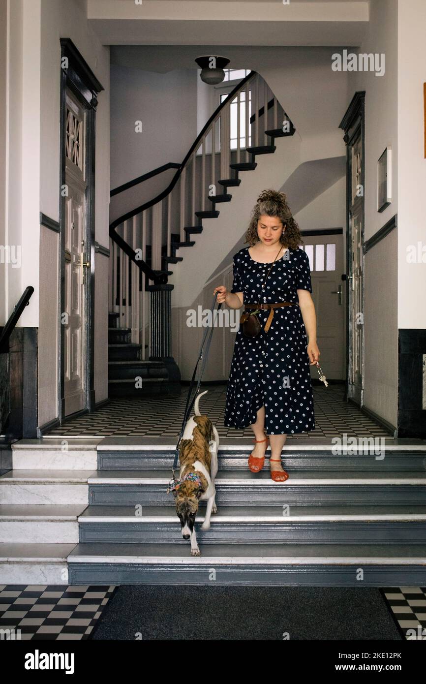 Donna che scende sui gradini con il cane Foto Stock