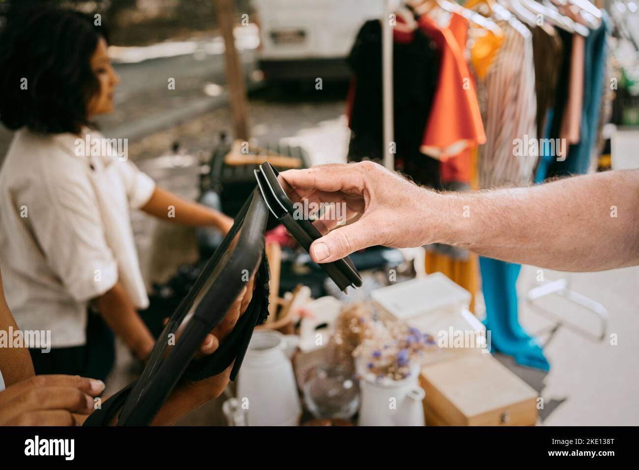 Mano di cliente maschio che paga via il rubinetto per pagare mentre acquista al mercato delle pulci Foto Stock