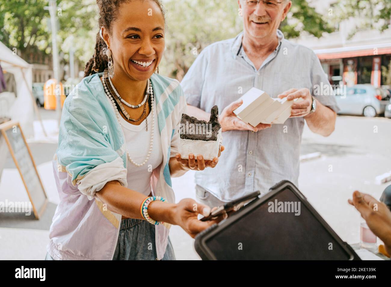 Sorridente cliente femmina modello di casa mentre fare il pagamento mobile al mercato delle pulci Foto Stock