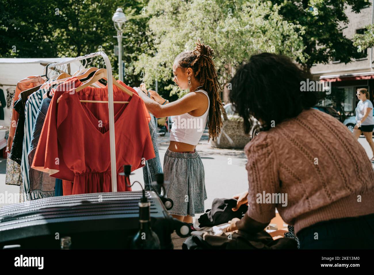 Vista laterale dell'abito appeso per una cliente femminile in rack mentre si acquista al mercato delle pulci Foto Stock