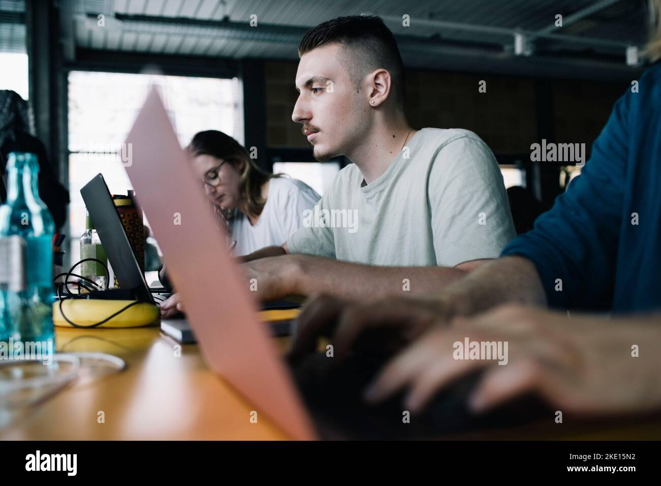 Uomo d'affari concentrato che lavora sul laptop tra i colleghi della startup Company Foto Stock