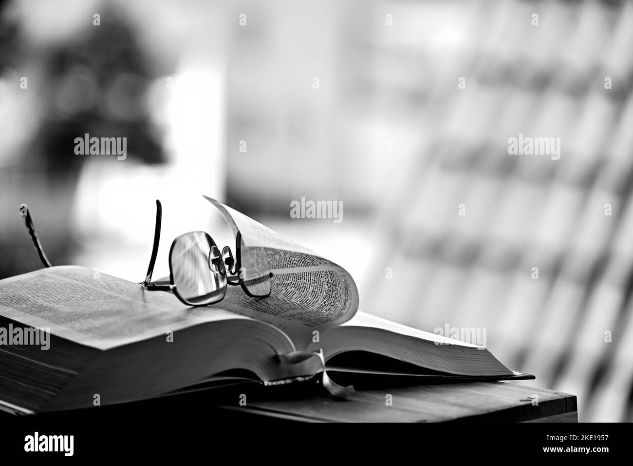 Un primo piano in scala di grigi di un libro aperto e bicchieri Foto Stock