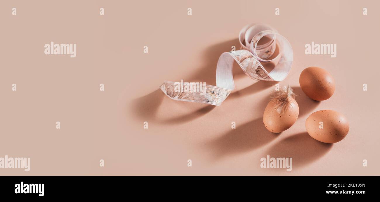 Sfondo pasquale con uova di colore naturale e piume marroni Foto Stock