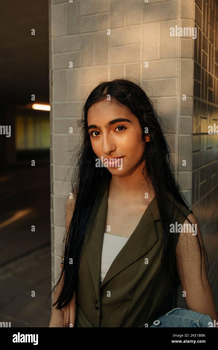 Ritratto di ragazza adolescente con capelli lunghi in piedi contro colonna Foto Stock