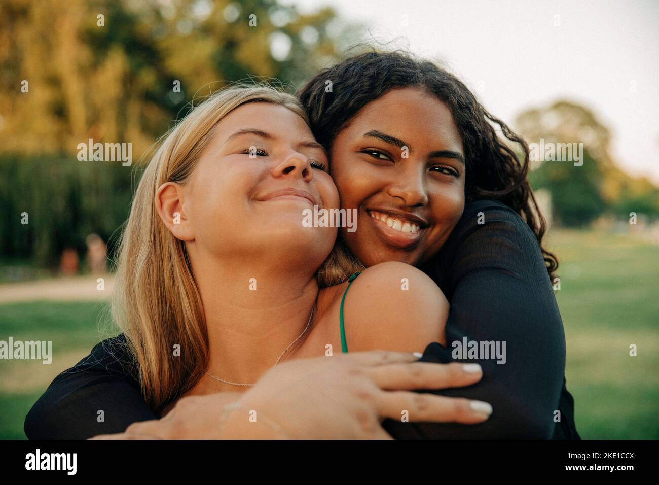 Felice ragazza adolescente abbracciando amico femmina con gli occhi chiusi Foto Stock