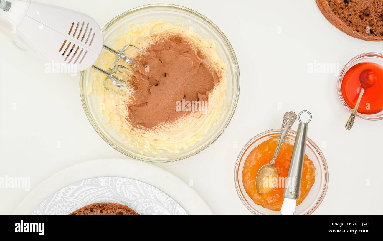 Mescolare la crema di burro con il cacao in polvere. Passo dopo passo ricetta torta al cioccolato, primo piano ingredienti su tavolo da cucina, piatto Foto Stock