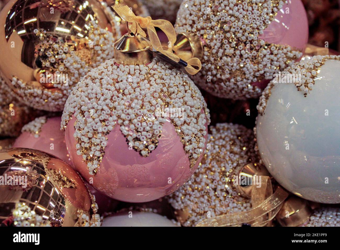 Palline di Natale luminose e brillanti in rosa, bianco e oro, decorate con oro e perle con un nastro. Sfondo di Natale. Spazio di copia Foto Stock