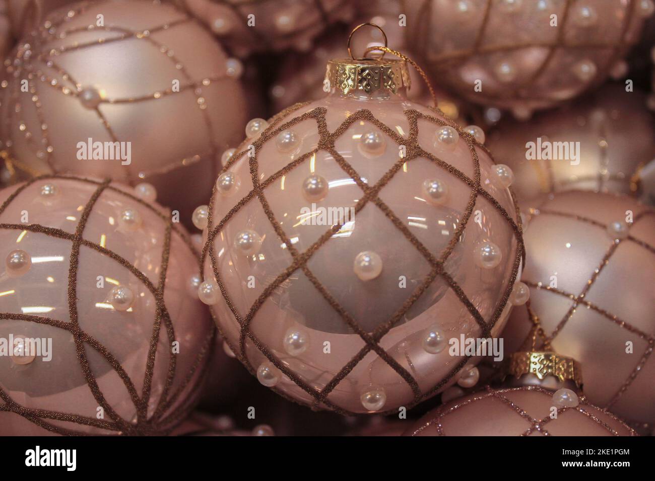Palline di Natale lucenti di delicato colore rosa, con una griglia d'oro decorata con perle. Sfondo gentile di Natale. Spazio di copia Foto Stock