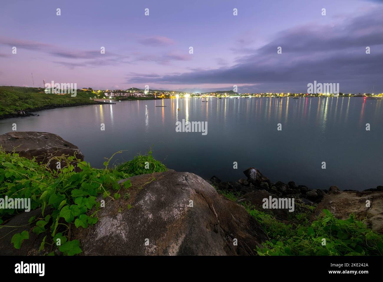 Le luci della città di Puerto Baquerizo Moreno iniziano a illuminarsi al crepuscolo sull'isola di San Cristobal, nelle isole Galapagos, Ecuador Foto Stock
