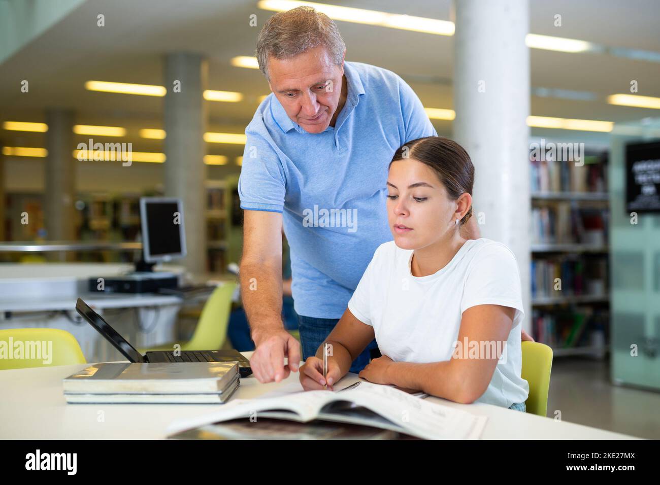 L'anziano bibliotecario aiuta gli studenti a trovare le informazioni di cui ha bisogno Foto Stock