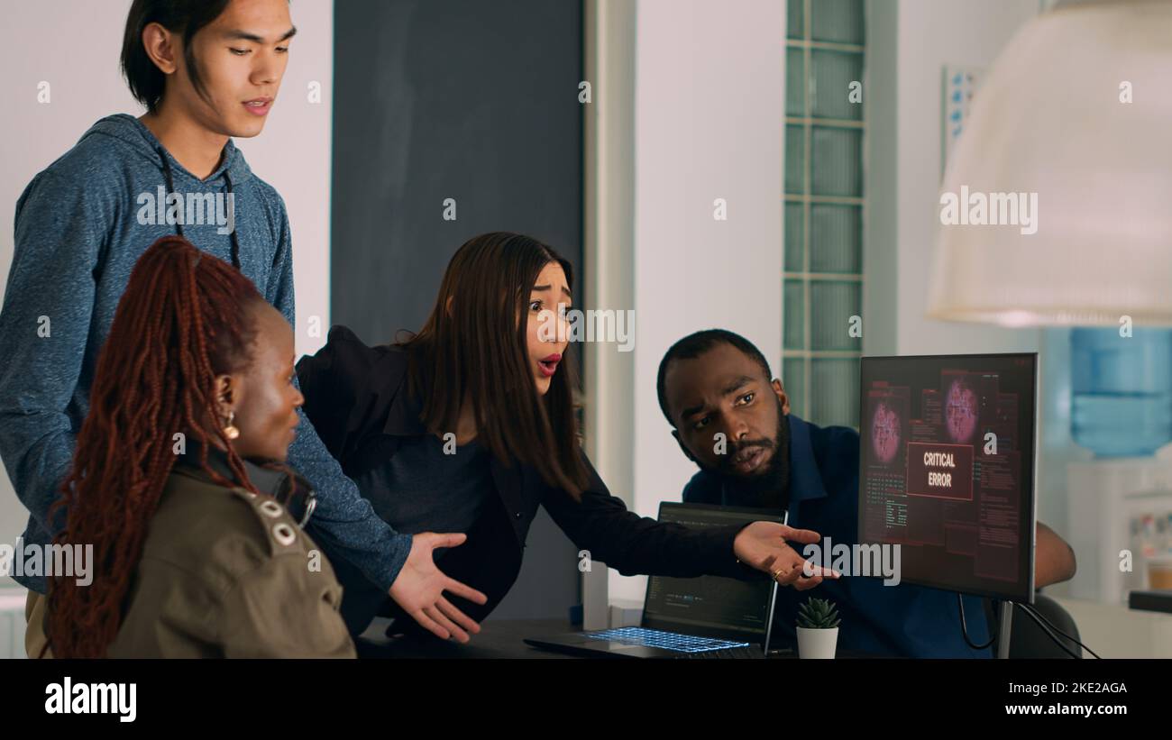 Un team di codificatori diversificato che si occupa dell'avviso di violazione della sicurezza sul computer, cercando di risolvere gli attacchi di hacking e gli errori critici. Ingegneri che utilizzano la finestra del terminale e che hanno violato il sistema crash. Foto Stock
