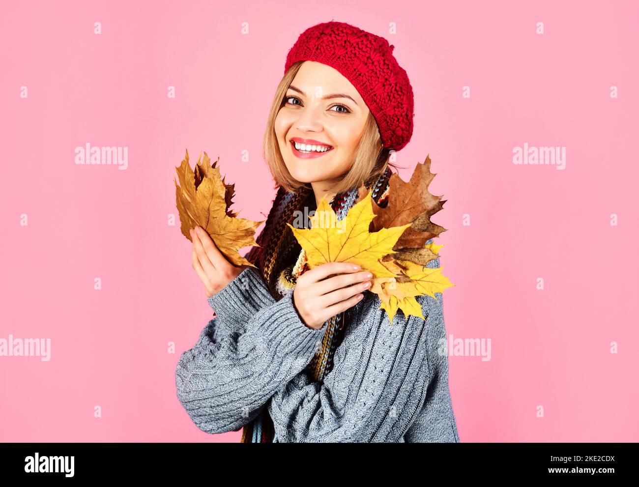 Donna sorridente in abiti caldi con foglie gialle. Umore autunnale. Vendita stagionale. Sconto. Spazio di copia. Foto Stock