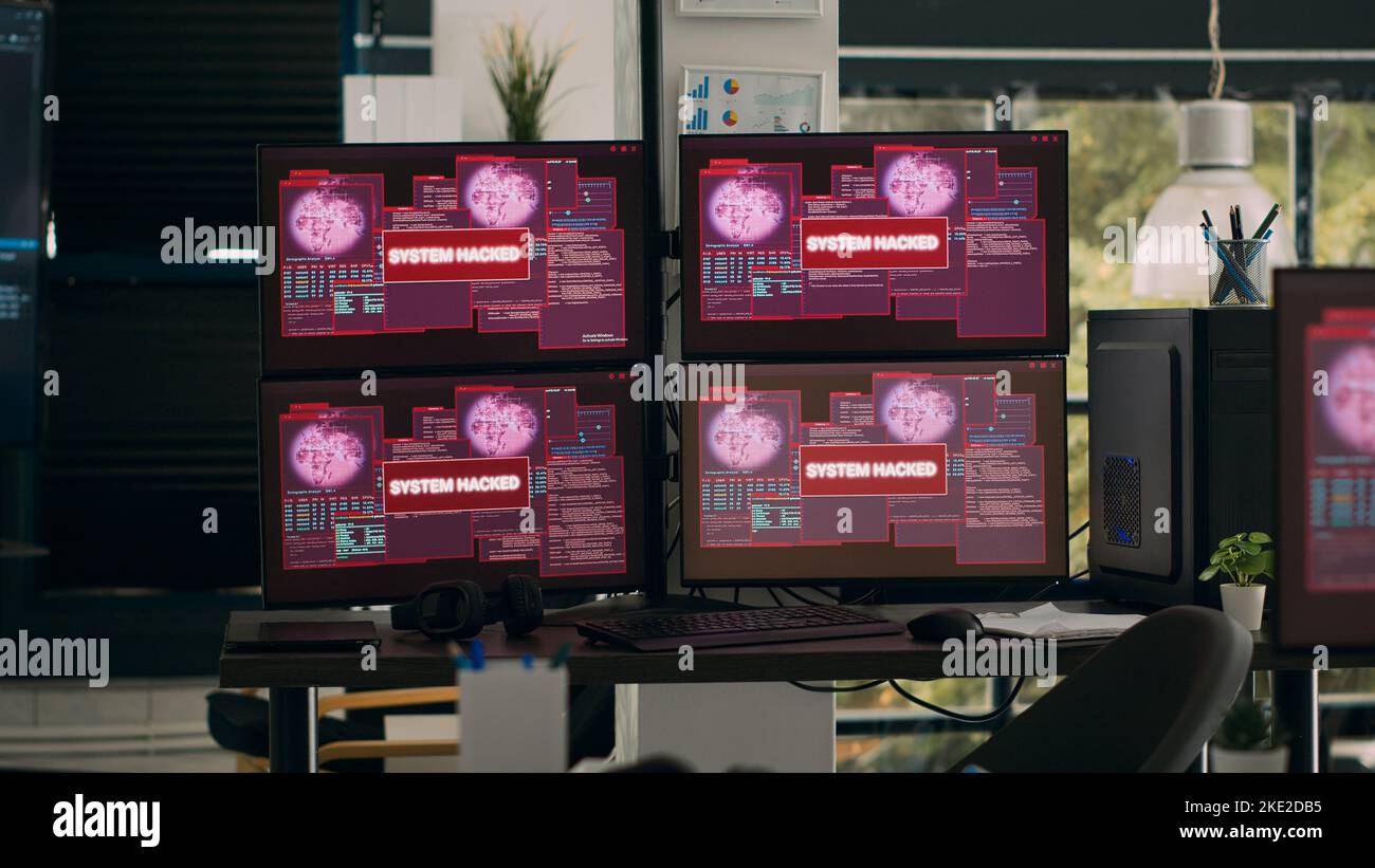 Più monitor con messaggio di errore critico lampeggiante sulle schermate con avviso di pirateria informatica e arresto anomalo del sistema. Scrivania vuota con computer che mostrano un avviso di violazione della sicurezza e un malfunzionamento del sistema. Foto Stock
