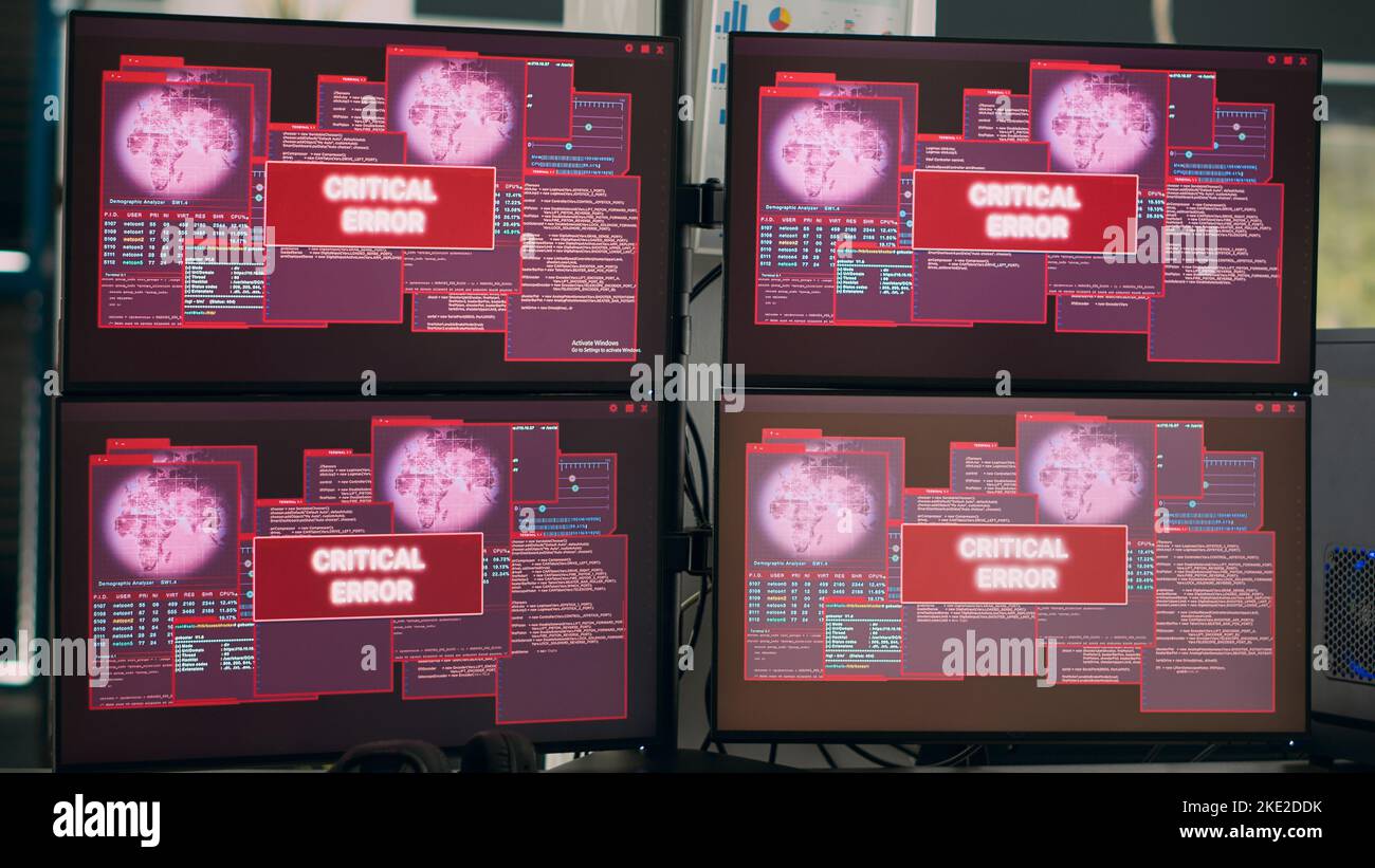 I computer che visualizzano un messaggio di errore critico lampeggiano sullo schermo, mostrando un avviso di pirateria informatica e un avviso di violazione della sicurezza. Svuotare l'ufficio IT con più monitor che eseguono attacchi informatici. Foto Stock
