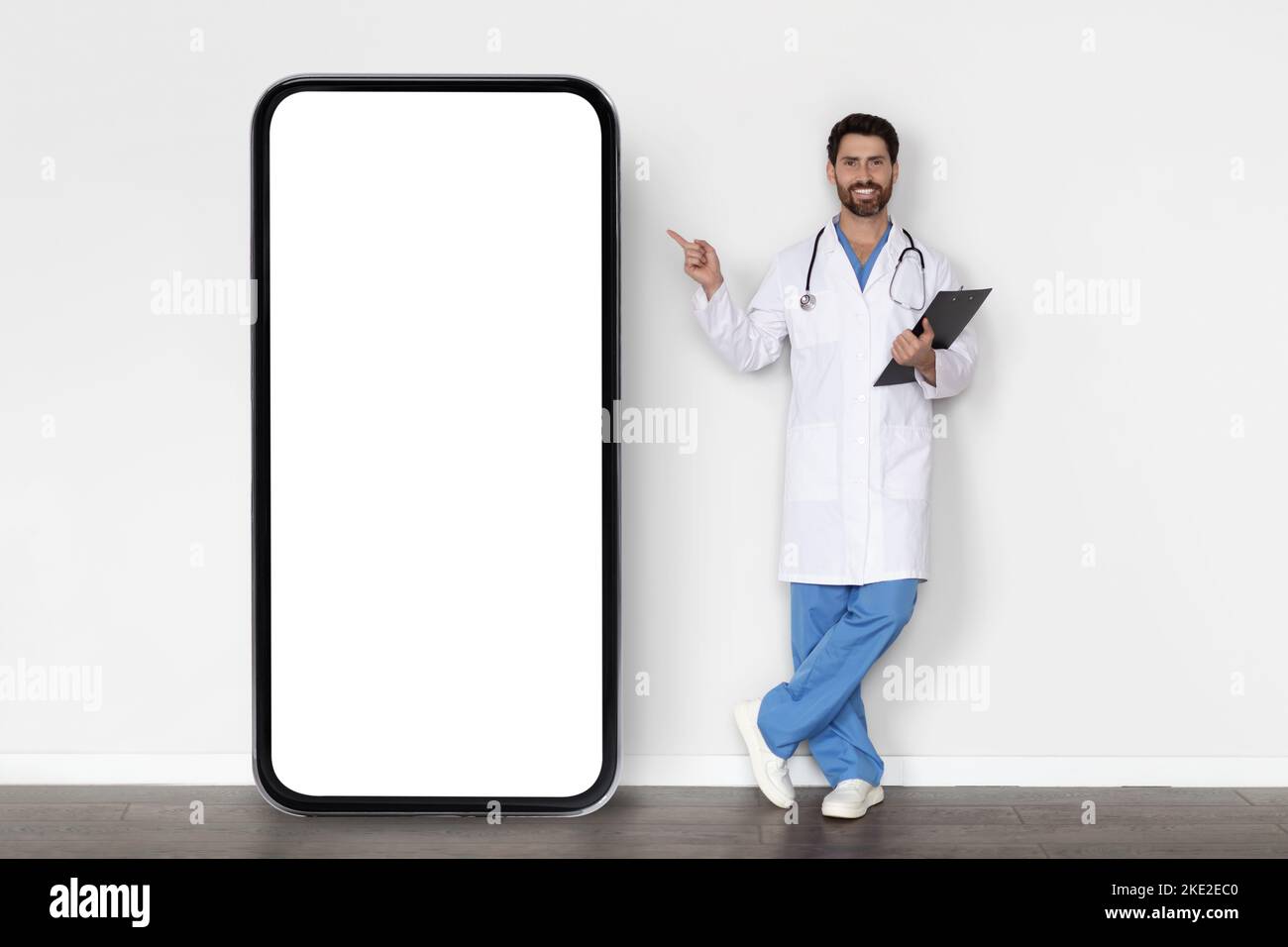 Offerta medica. Medico maschile in uniforme punta dito a Big Blank smartphone Foto Stock