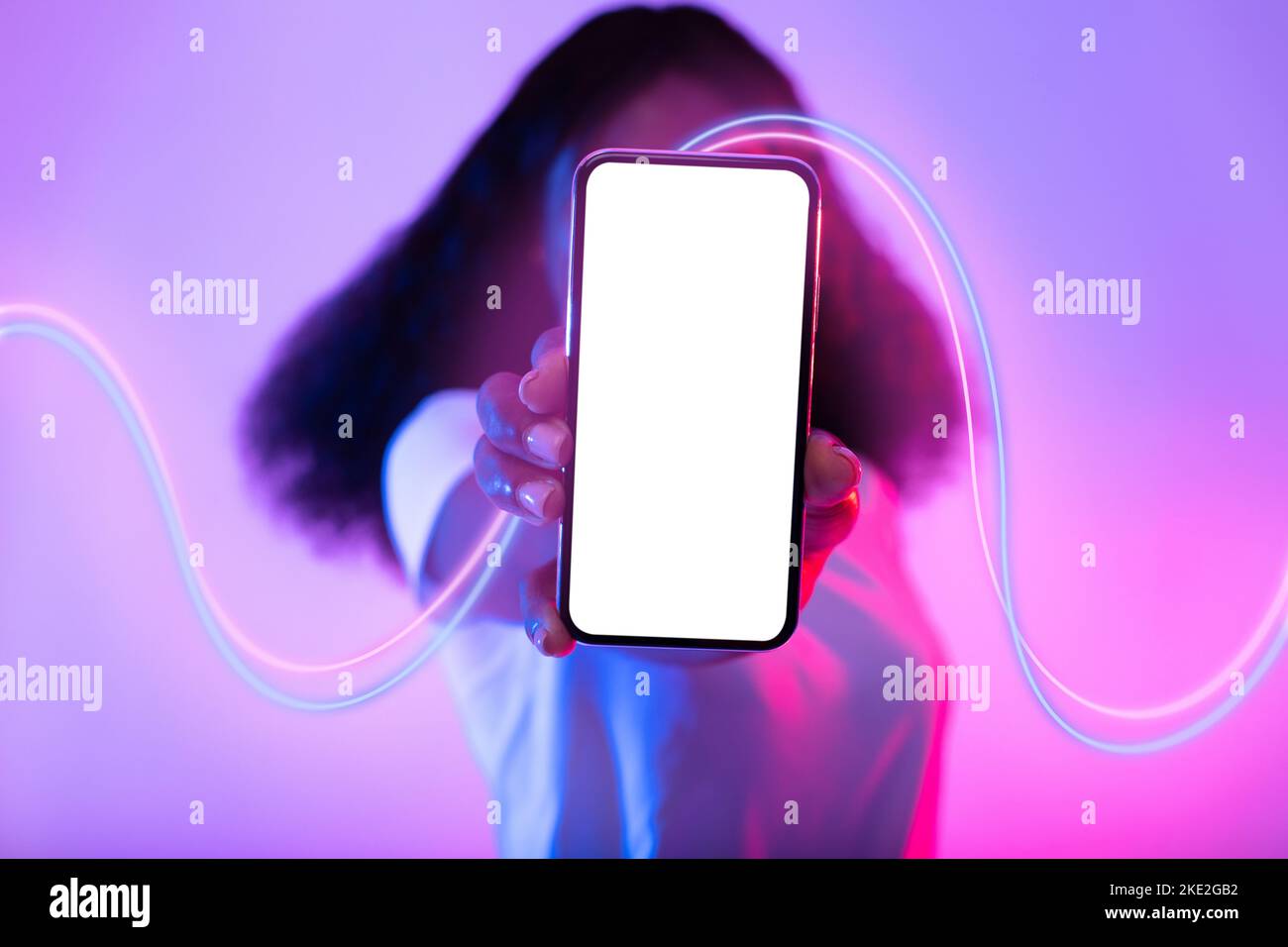 Donna nera irriconoscibile che si nasconde dietro il telefono con schermo vuoto, mockup Foto Stock
