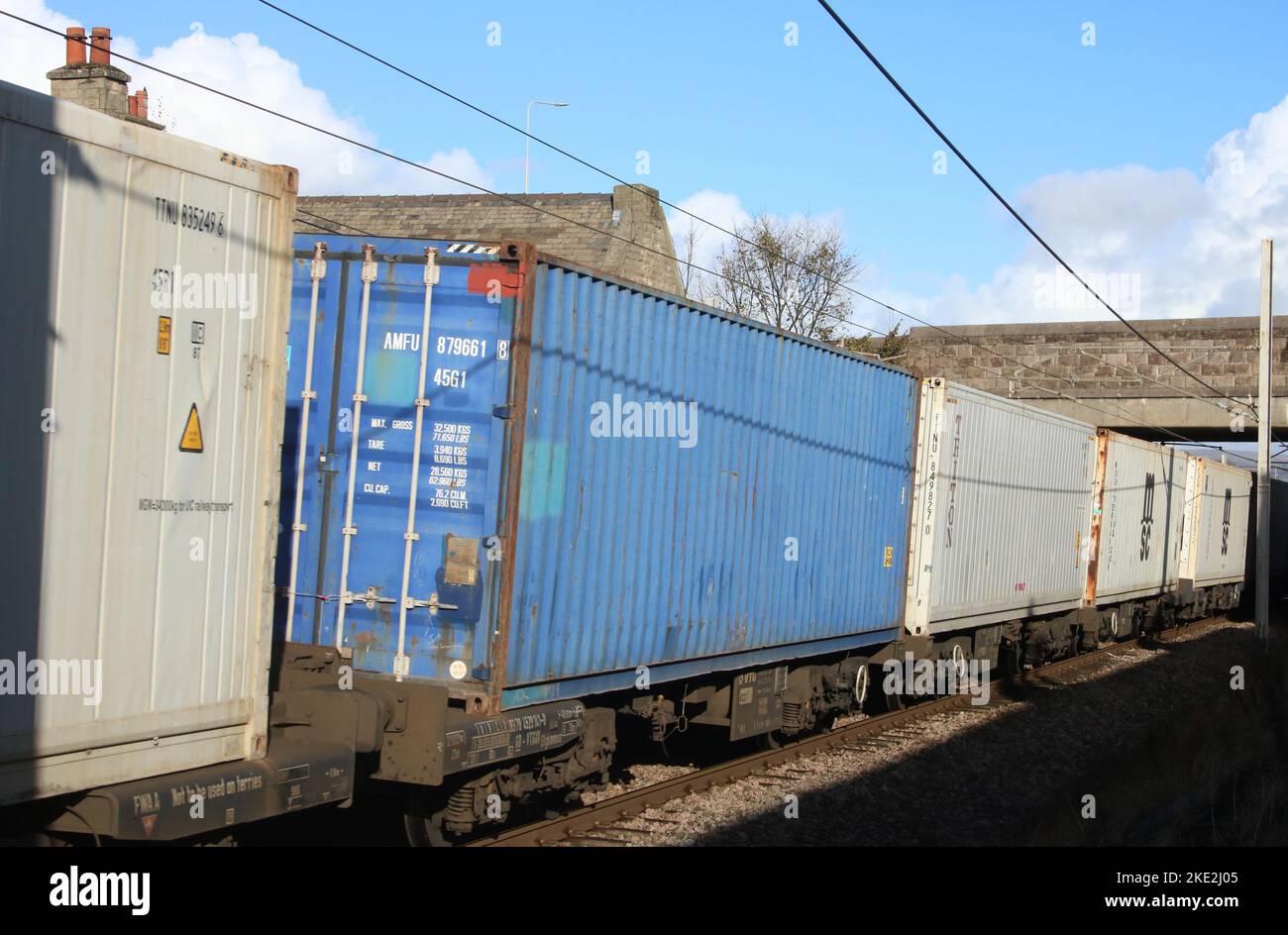 Vista laterale dei container su un treno di container che attraversa Carnforth sulla West Coast Main Line il 9th novembre 2022. Foto Stock