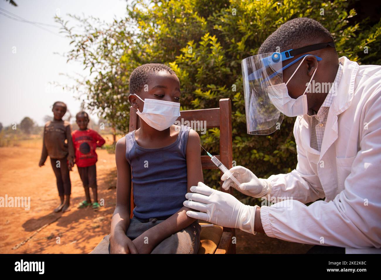 Sessione di vaccinazione all'aria aperta in un villaggio africano durante la pandemia del virus corona. Foto Stock