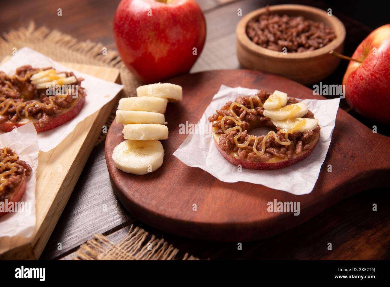 Festa creativa snack per le vacanze. Le mele si arrotolano con burro di arachidi, caramello e cioccolato farcitura di riso soffiato con fette di banana. Appetiz divertente Foto Stock