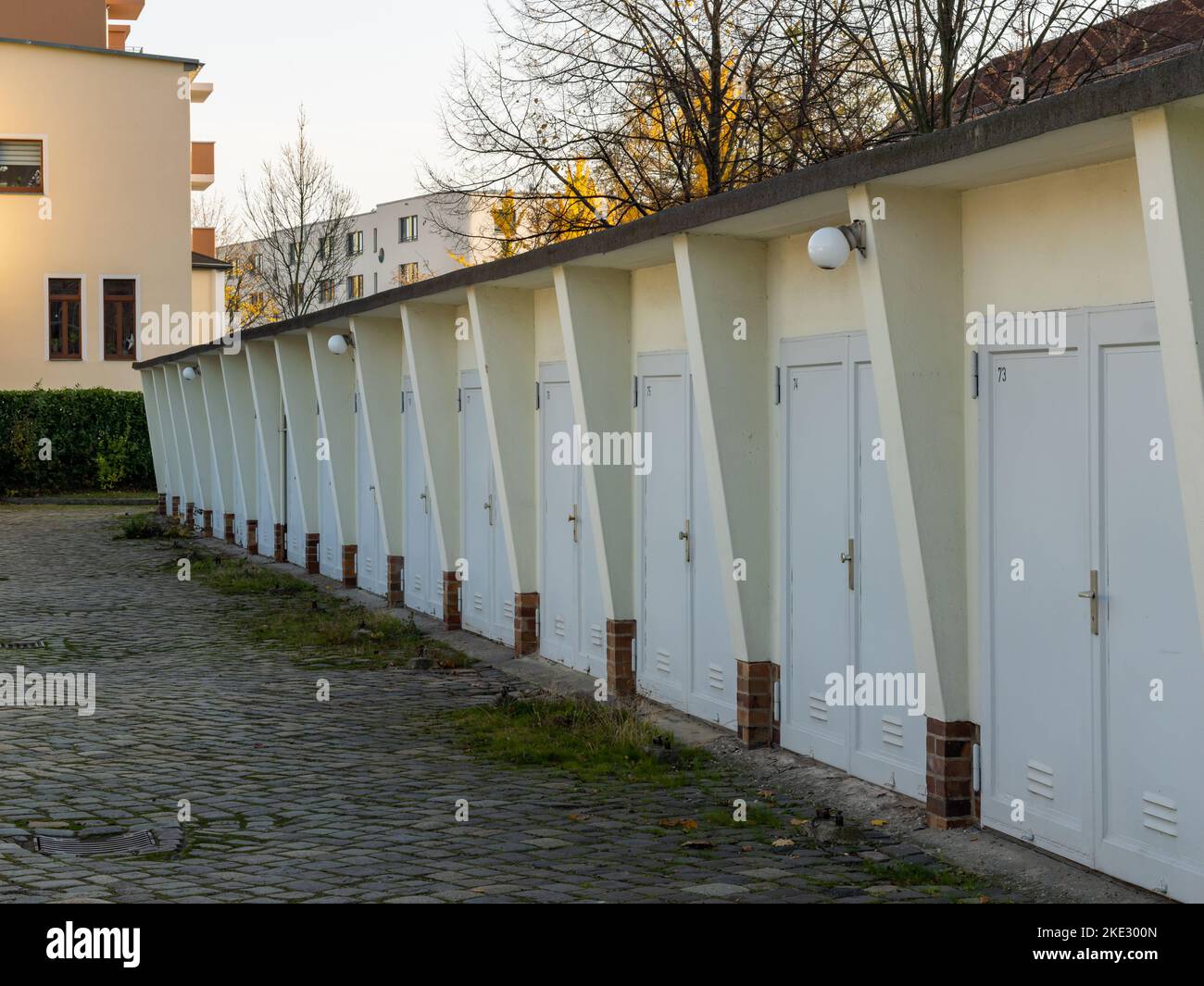 Molte porte da garage di un lungo edificio in fila. Parcheggio residenziale in una città. Lo spazio è limitato per un numero elevato di auto e altri veicoli. Foto Stock