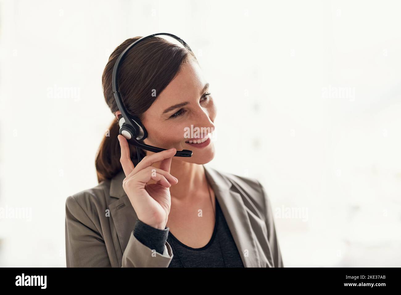 Gestire ogni richiesta con un sorriso. Un giovane agente di supporto che lavora in un ufficio. Foto Stock