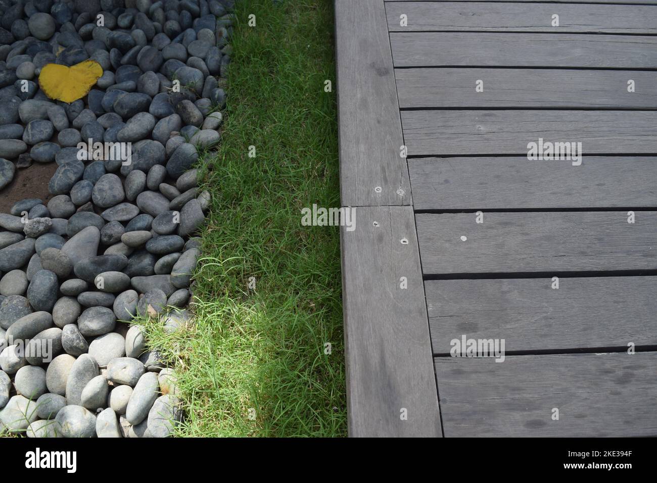 Contrasto di materiali naturali dalla pietra all'erba per recuperare la pavimentazione in legno. Foto Stock