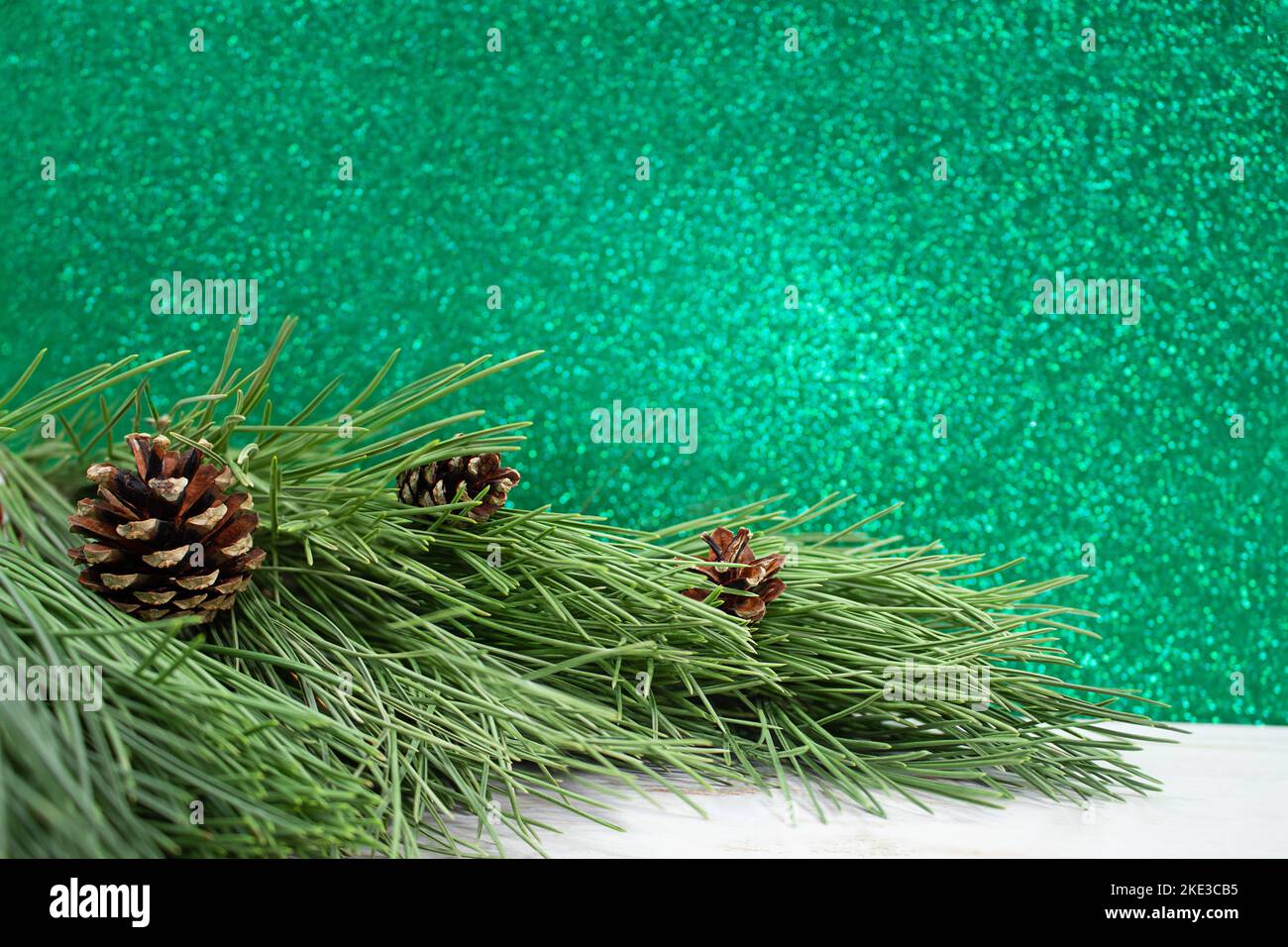Rami di pino naturale con coni su tavola bianca. Bokeh verde sfocato. Natale, Capodanno. Spazio di copia Foto Stock