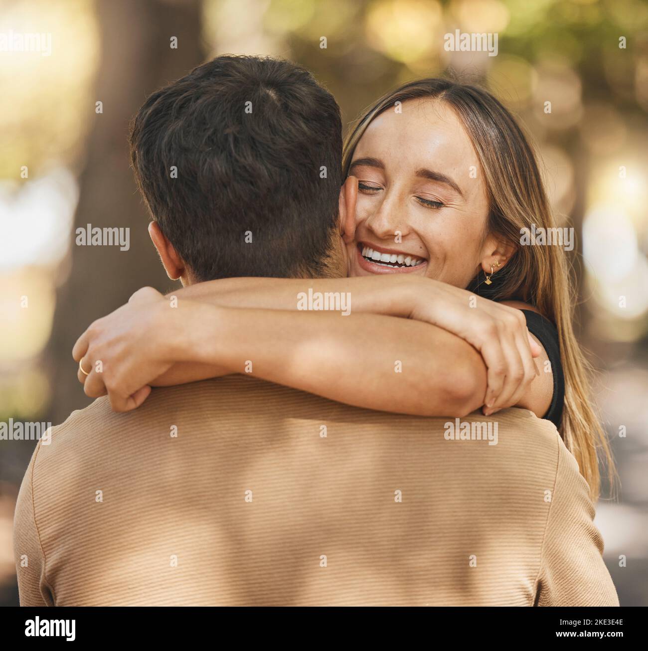 Abbraccia, ama e coppia in un appuntamento in un parco con un sorriso, felice e romantico nella natura. La cura, la felicità e l'uomo e la donna che abbraccia per affetto, dispersi Foto Stock