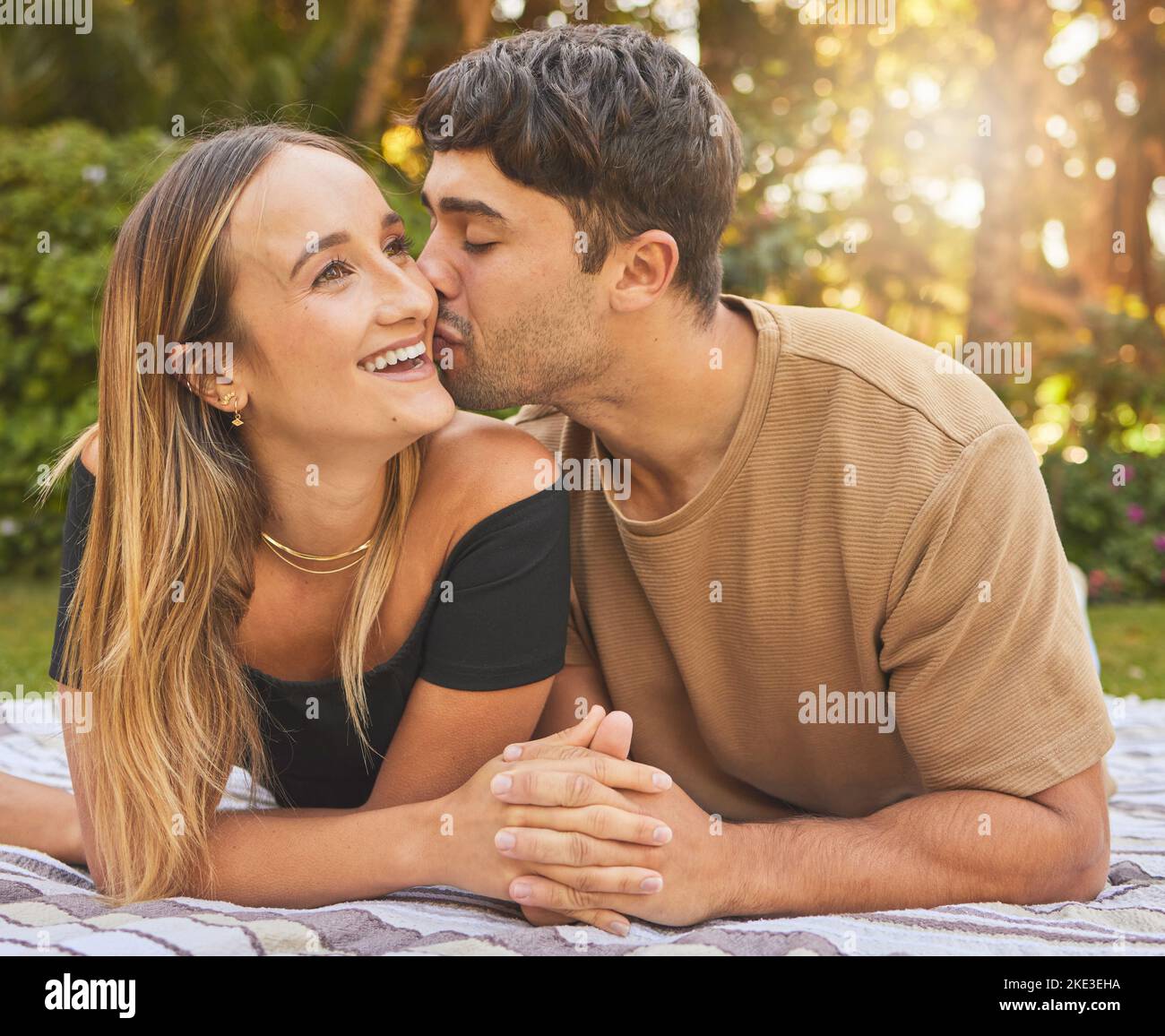 Coppia, tenendo le mani con bacio e amore nel parco, pic-nic per il legame e felice nella natura insieme. Supporto, fiducia e cura con data romantica e. Foto Stock