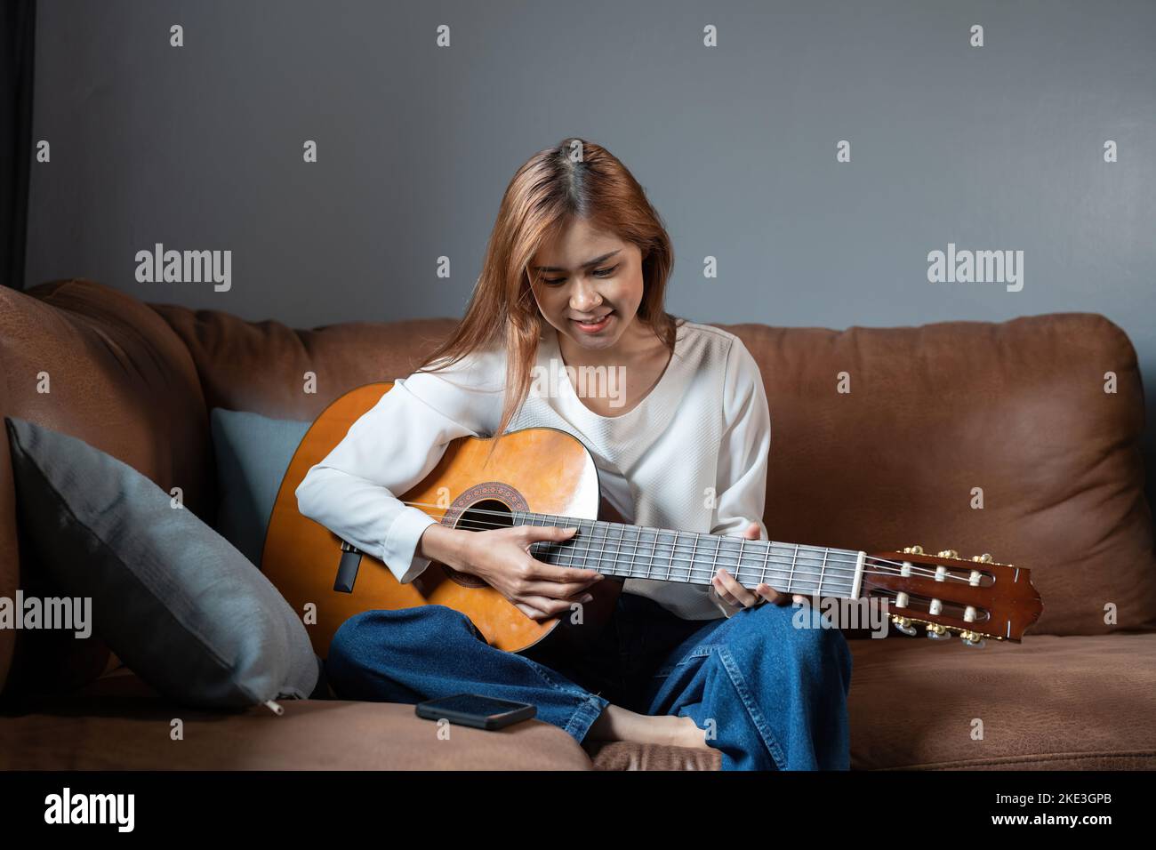 Immagine di una bella donna felice che suona la chitarra e compone la canzone. Foto Stock