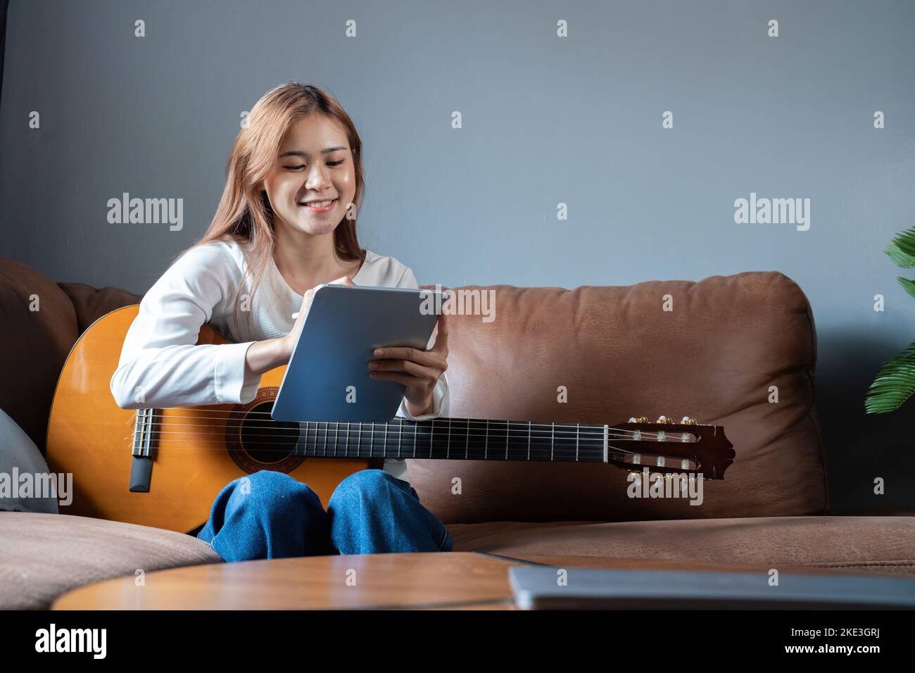Immagine di una bella donna felice che suona la chitarra e compone la canzone Foto Stock