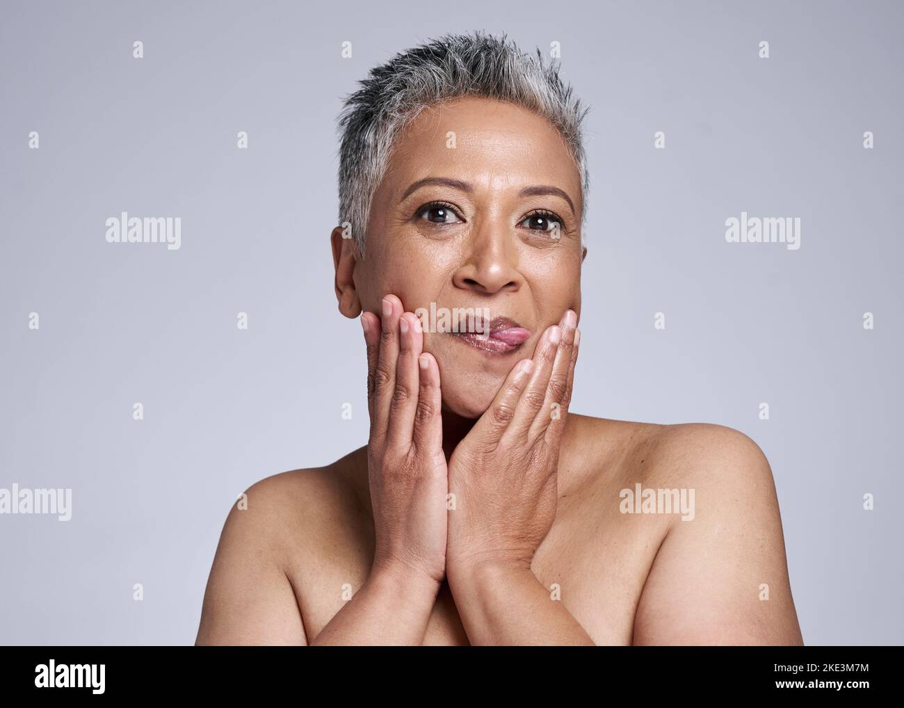 Skincare, fumetto e modello senior con bellezza, cosmetici e viso naturale routine in studio. Goofy, benessere e ritratto di anziana signora con lingua Foto Stock