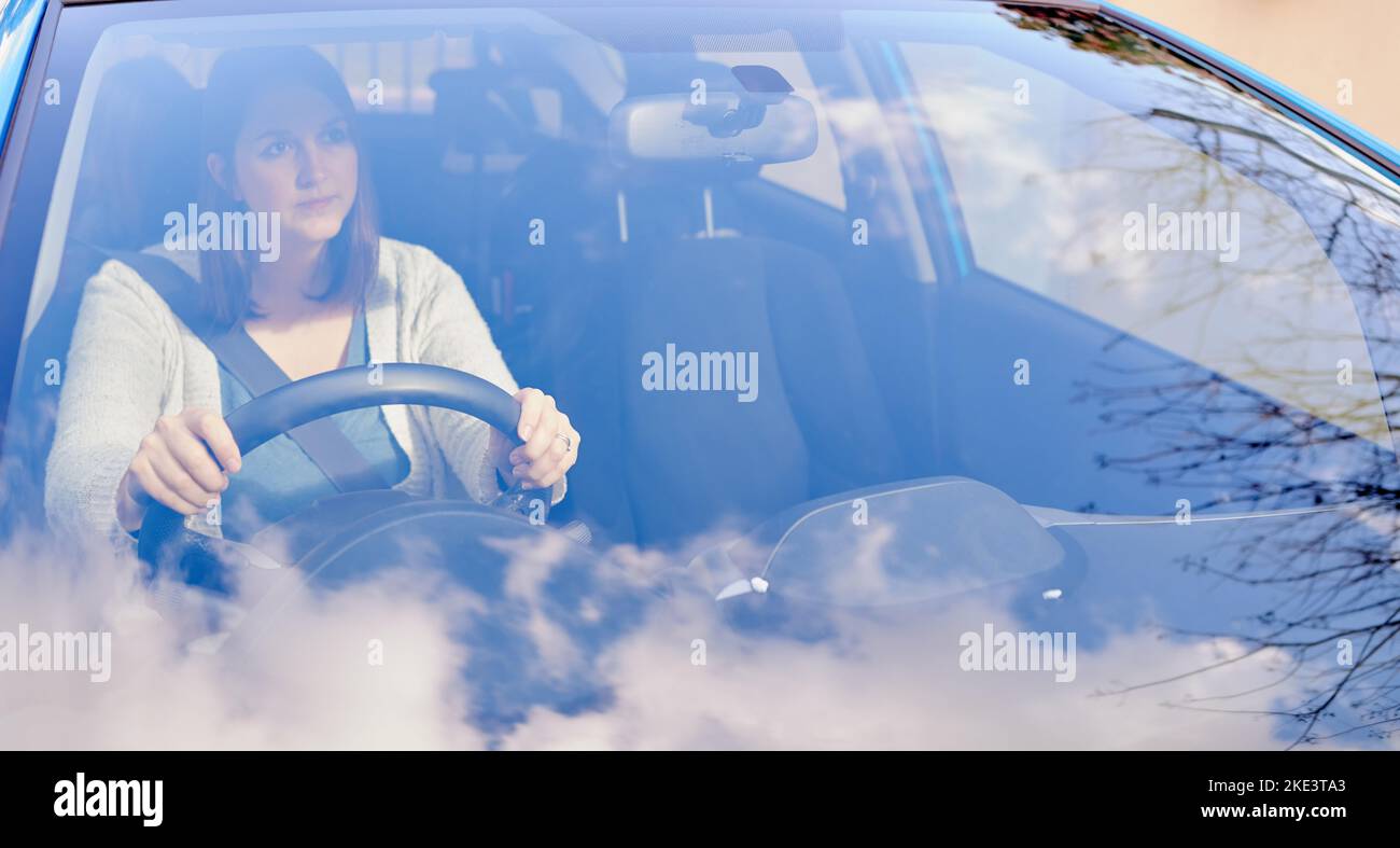 I conducenti difensivi sono conducenti più sicuri, una giovane donna che guarda attraverso il parabrezza della sua auto durante la guida. Foto Stock