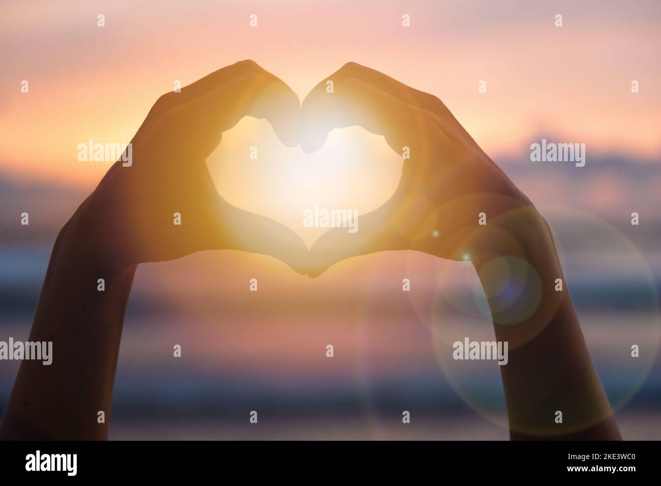 Le mani formano un cuore con la silhouette del tramonto Foto Stock