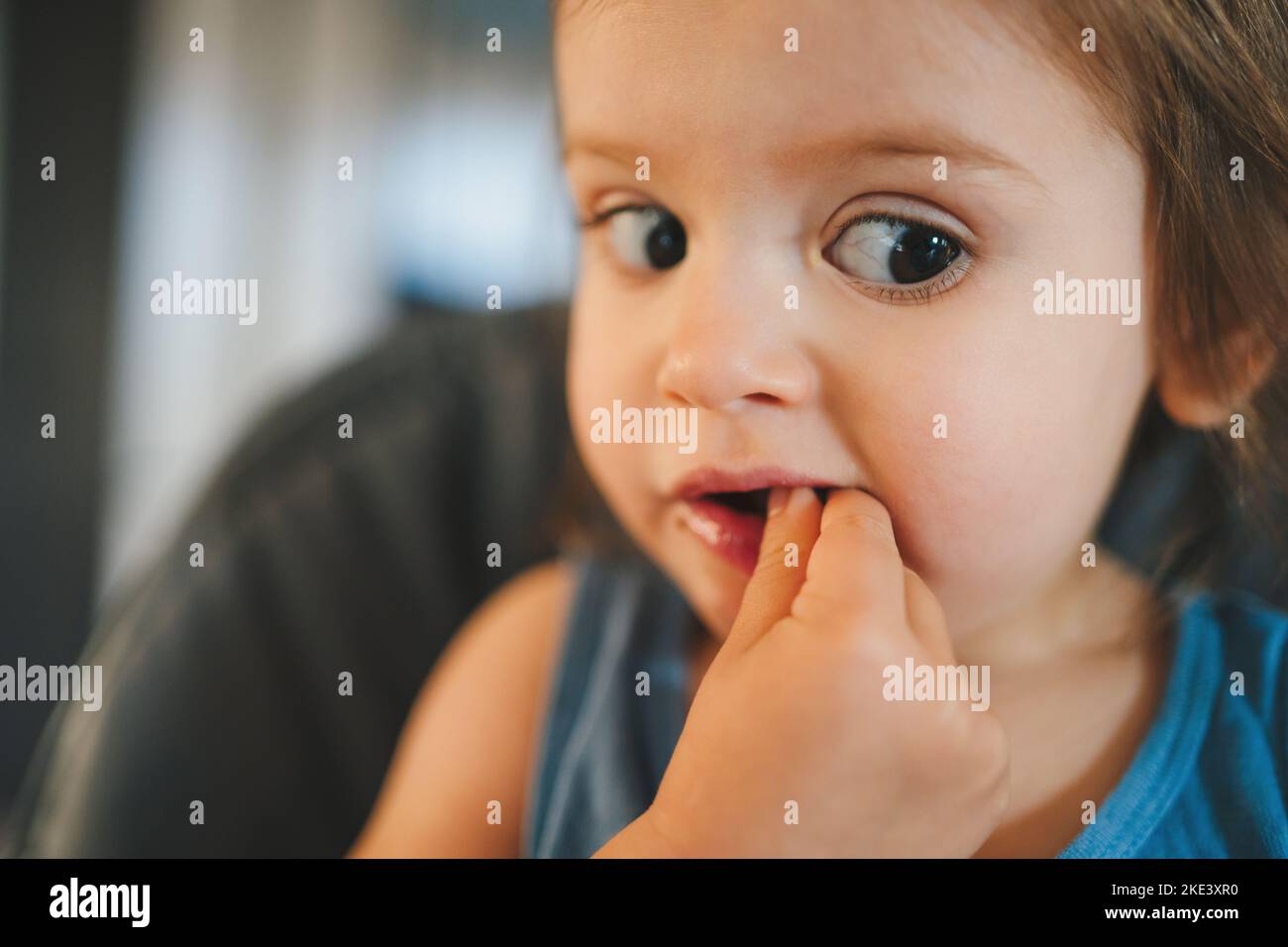 Primo piano ritratto di una ragazza che guarda concentrata su un lato tenendo le mani in bocca. Nutrizione sana per i bambini. Bambini , la sicurezza dei bambini. Foto Stock