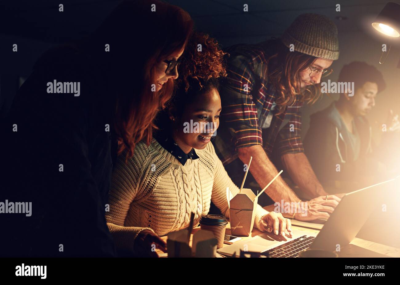 Fare del loro meglio per produrre un lavoro di qualità. Un team aziendale che utilizza un notebook insieme durante un turno di notte al lavoro. Foto Stock